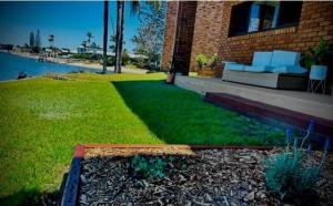 a house with a lawn with a couch in front of it at Barooga1- Mooloolaba Canal Front Apartment in Mooloolaba +11 photos