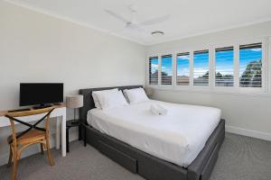 Un dormitorio con una cama y un escritorio con televisión. en TARA7- On Trend At Taranaki, en Mooloolaba