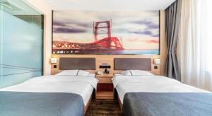 deux lits dans une chambre avec un tableau représentant un pont dans l'établissement Jun Hotel Anhui Bozhou Lixin County Wenzhou Road, à Chundian