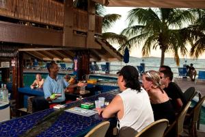 Bolongo Bay Beach Resort All Inclusive في Bolongo: مجموعة من الناس يجلسون على طاولة على الشاطئ