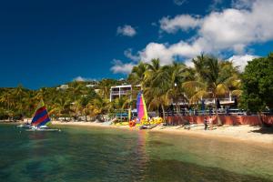 three sailboats on the shore of a beach with palm trees at Bolongo Bay Beach Resort All Inclusive in Bolongo