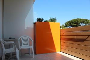 une terrasse avec une clôture, 2 chaises et une table dans l'établissement Hotel Alex, à Lignano Sabbiadoro