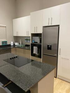 a kitchen with white cabinets and a stainless steel refrigerator at Sunset at 30 Nivica Luxury Apartment in Langebaan