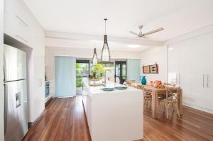 a kitchen and dining room with white cabinets and a table at Jalun Bayun The Sea House in Newell Beach