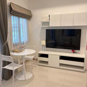 Una sala de estar con un televisor grande y una mesa. en Home in Bang Po Beach Koh Samui, en Nathon Bay