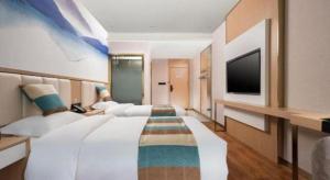 une grande chambre avec deux lits et une télévision à écran plat dans l'établissement VX Hotel Beijing Daxing Wufutang Metro Station Zhongke Dianshanggu, à Pékin