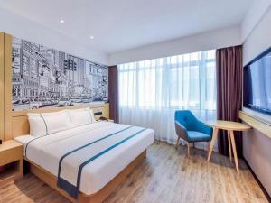 une chambre d'hôtel avec un lit et une chaise bleue dans l'établissement City Comfort Inn Chongqing Yongchuan Xuefu Avenue Wanda, à Yongchuan