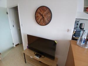 une horloge sur le mur au-dessus d'une télévision sur un mur dans l'établissement Agréable T2 a 3mn de la mer parking wifi, à Six-Fours-les-Plages