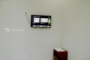 Elle comprend une télévision à écran plat sur un mur blanc et une boîte. dans l'établissement Dieng Top Syariah By Travelink, à Diyeng