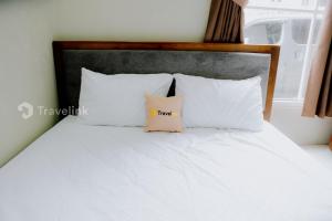 - un lit blanc avec des oreillers blancs et une tête de lit en bois dans l'établissement Dieng Top Syariah By Travelink, à Diyeng