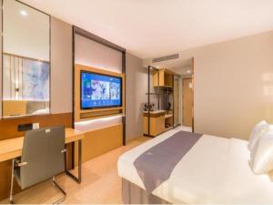 Un dormitorio con una cama, un escritorio y un televisor. en GreenTree Eastern Hotel Tianjin Dongli Development Zone Xinli Metro Station, en Tianjin