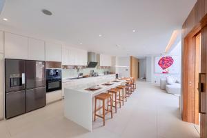 a kitchen with white cabinets and a long island with bar stools at Designer 3BR Pool Villa in New Build LuxPride 4 L8 Residence in Ban Pak Lak