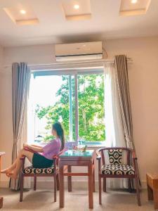 a woman sitting at a table in front of a window at Ngoc Bach Hotel in Mai Chau