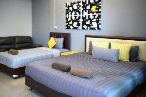 a bedroom with two beds and a couch at Nithra Ratree Hotel in Si Maha Phot