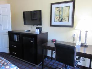 a hotel room with a desk and a television at Executive Inn and Suites Tyler in Tyler