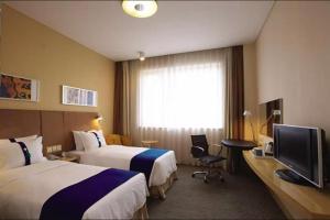 ein Hotelzimmer mit zwei Betten und einem Fernseher in der Unterkunft Holiday Inn Express Zhangye By IHG in Zhangye