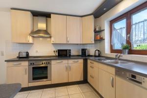 a kitchen with wooden cabinets and a sink and a window at Ferienhaus am Mühlenbach, 110qm in Schwanau