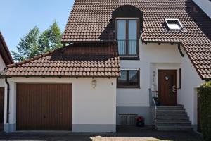 a white house with a gate and a garage at Ferienhaus am Mühlenbach, 110qm in Schwanau