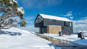 a building in the snow next to a river at Peak Chalet in Mount Hotham