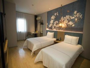 a hotel room with two beds and a painting on the wall at Jinjiang Inn Tianjin Station Jinwan Square in Tianjin +197 photos