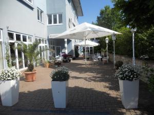a patio with potted plants and an umbrella at Rheinhessen Inn GmbH in Wörrstadt