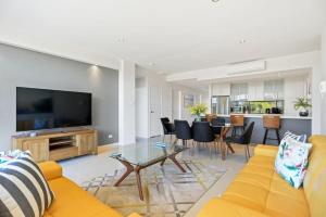 Una sala de estar con un sofá amarillo y una mesa. en Aqua Shores - 1 Bedroom couples stay - Wifi, Linen, Netflix and AC, en Huskisson