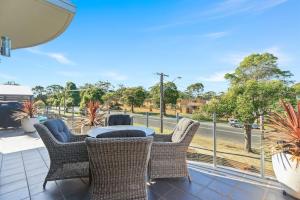 patio con sillas de mimbre y mesa en el balcón en Aqua Shores - 1 Bedroom couples stay - Wifi, Linen, Netflix and AC, en Huskisson 2 fotos más