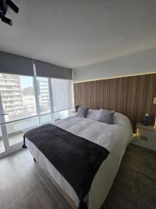 a bedroom with a large bed and large windows at Departamento en Santiago, Parque O'higgins, Movistar Arena con terraza in Santiago