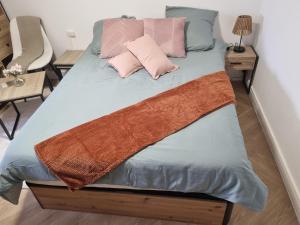 a bed with pink and blue sheets and pillows at Golden Cottage Stade P Mauroy Lille in Villeneuve d'Ascq