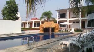 a swimming pool with chairs and a fountain in front of a building at Hotel Real de Cuautla in Cuautla Morelos