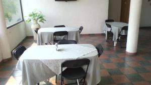 Habitación con 2 mesas y sillas con mantel blanco en Hotel Real de Cuautla, en Cuautla Morelos