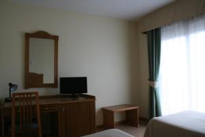 a bedroom with a desk with a television and a mirror at Hotel Austria 76 in Puerto de Sagunto