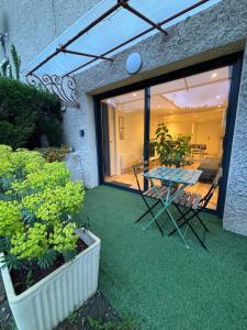 a patio with a table and chairs and some plants at Appartement chez maison hôte rez de jardin in Charmeil