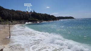 a beach with a wave in the water at Apartments Seafront Villa in Pula