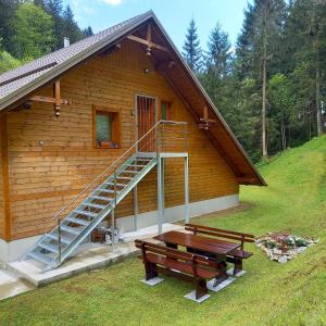 a log cabin with a staircase and a picnic table at Hiša Lunna - Apartments in a Forest Paradise in Vitanje