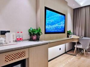 a living room with a television on a wall at Gya Hotel Jurong England International in Zhenjiang