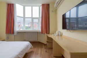 a bedroom with a bed and a desk and two windows at 7Days Inn Tianjin Fifth Avenue Youyi Road Branch in Tianjin