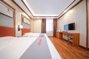 ein Hotelzimmer mit großem Bett und Schreibtisch in der Unterkunft Jun Hotel Guangxi Wuzhou Changzhou District Fengye Garden in Wuzhou