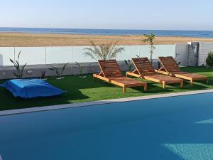 a group of chairs sitting next to a swimming pool at Blue Aura Beach villa Larnaca in Pervolia