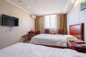 a hotel room with two beds and a flat screen tv at GreenTree Inn Wuxi Guangrui Road Hotel in Wuxi +267 photos