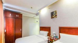 a hotel room with two beds and a cabinet at GreenTree Inn Shanghai South Railway Station Xujiahui Stadium Subway Station Shell Hotel in Shanghai