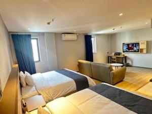 a hotel room with two beds and a chair at 7 Days Premium Jiangmen Wuyi Avenue Gangkou Road in Jiangmen