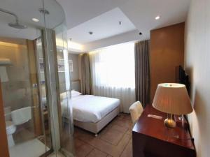 a hotel room with a bed and a desk with a lamp at Jinjiang Metropolo Shanghai Minhang in Shanghai +223 photos