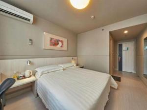 una camera da letto con un grande letto bianco e una scrivania di Jinjiang Inn Shanghai Qingpu a Shanghai