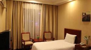 una stanza d'albergo con un letto e due sedie di GreenTree Inn Shanghai Gongkang Road Branch a Shanghai