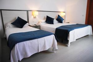 a hotel room with two beds with blue and white sheets at Parrots Sitges Hotel in Sitges