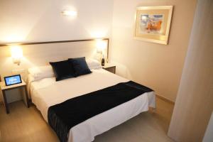 um quarto de hotel com uma cama com duas almofadas em Parrots Sitges Hotel em Sitges