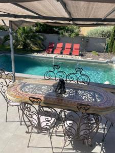 a patio table with chairs and a swimming pool at Villa Le Luberon in Mérindol