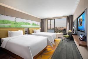 a hotel room with two beds and a flat screen tv at Hampton by Hilton Zhuhai Doumen in Zhuhai