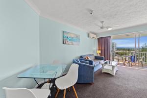 a living room with a blue couch and a glass table at Surf Parade Resort in Gold Coast
